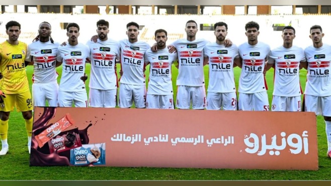 لاعبو الزمالك مصطفون أمام لوحة تحمل عبارة الراعي الرسمي للنادي داخل الملعب.