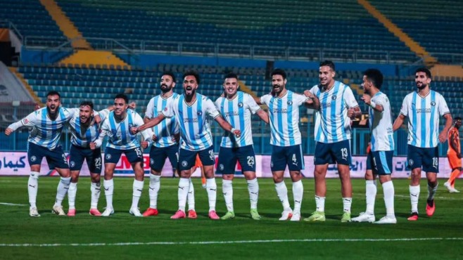 لاعبو كرة قدم مصطفون في الملعب أمام مدرجات الاستاد.