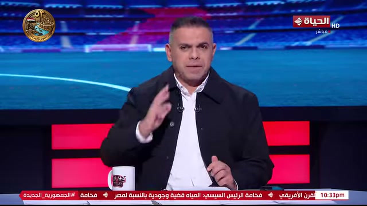 مقدم يجلس في استوديو قناة الحياة أمام خلفية رياضية.