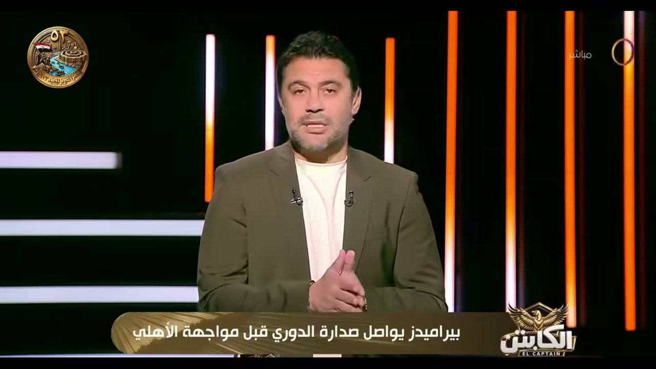 أحمد حسن في استوديو برنامج الكابتن على قناة DMC، مع ظهور شعار البرنامج في إطار البث.