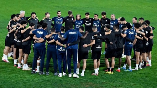لاعبو الزمالك والجهاز الفني يتجمعون في دائرة داخل الملعب.