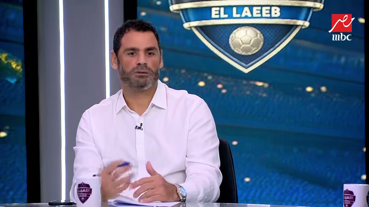 رجل يتحدث في استوديو برنامج رياضي أمام شعار البرنامج.